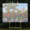 original oil painting by Nicole Athena of cypress trees in swamp with reflections on water displayed on easel