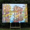 original oil painting by Nicole Athena of cypress trees in swamp with reflections on water displayed on easel